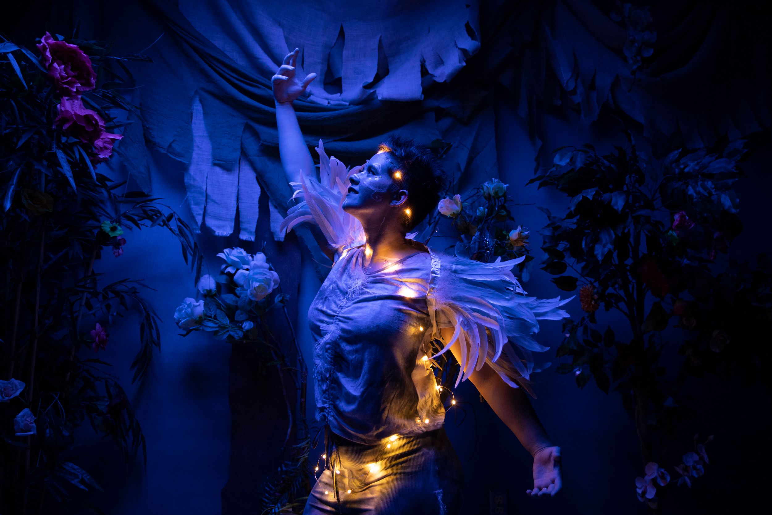 A student performing in Midsummer Night's Dream wearing a feathery costume and string lights.