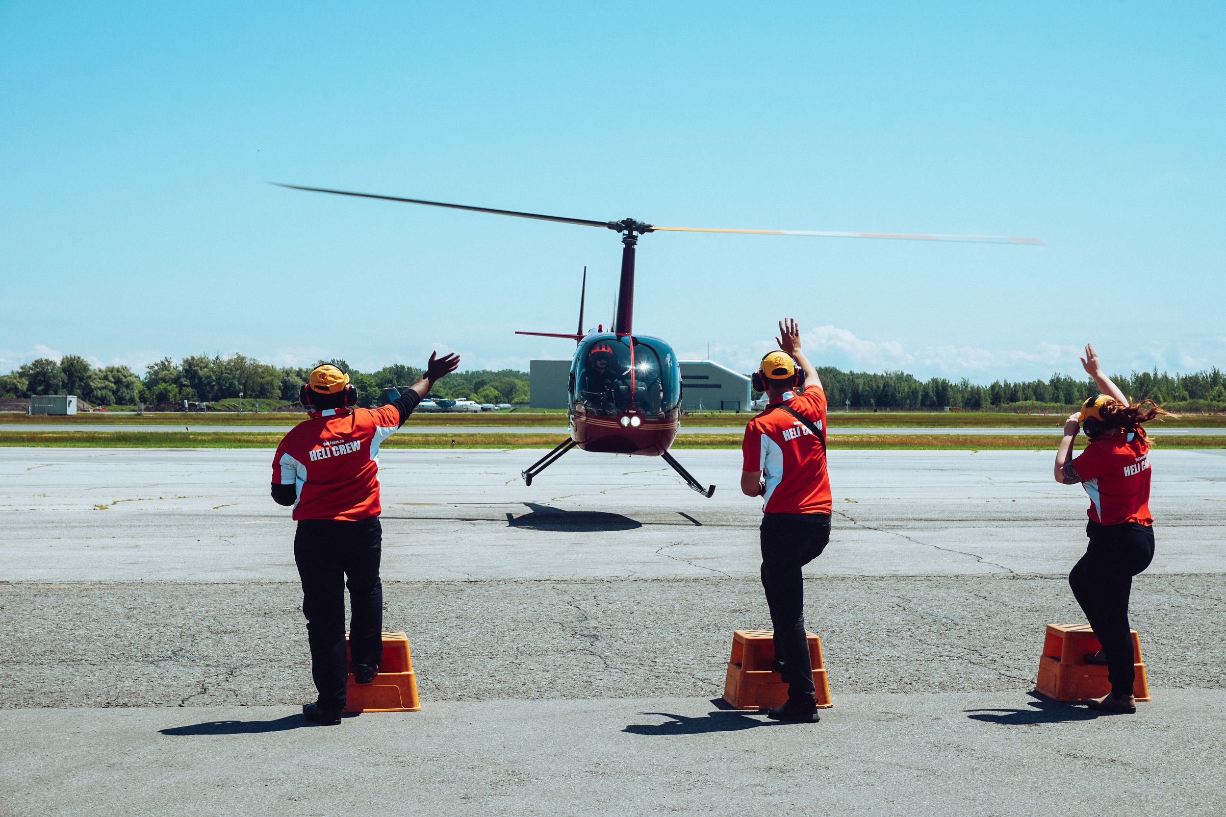 Three aircrew members guide a landing helicopter.