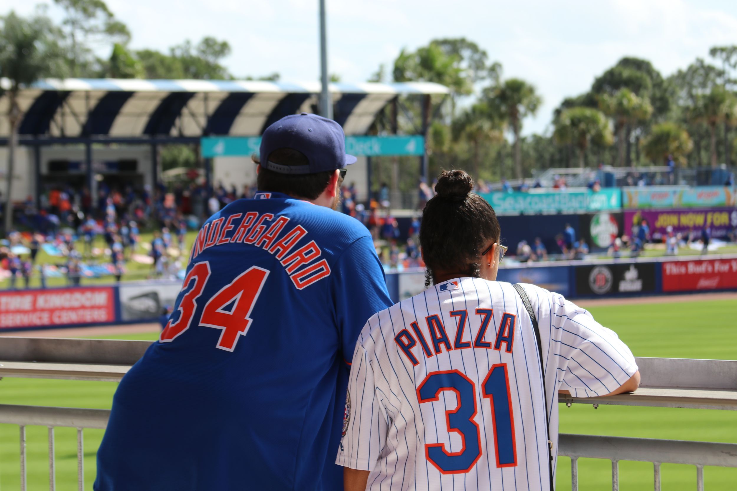 Two people in Mets jerseys enjoying a spring training game at Clover Park.