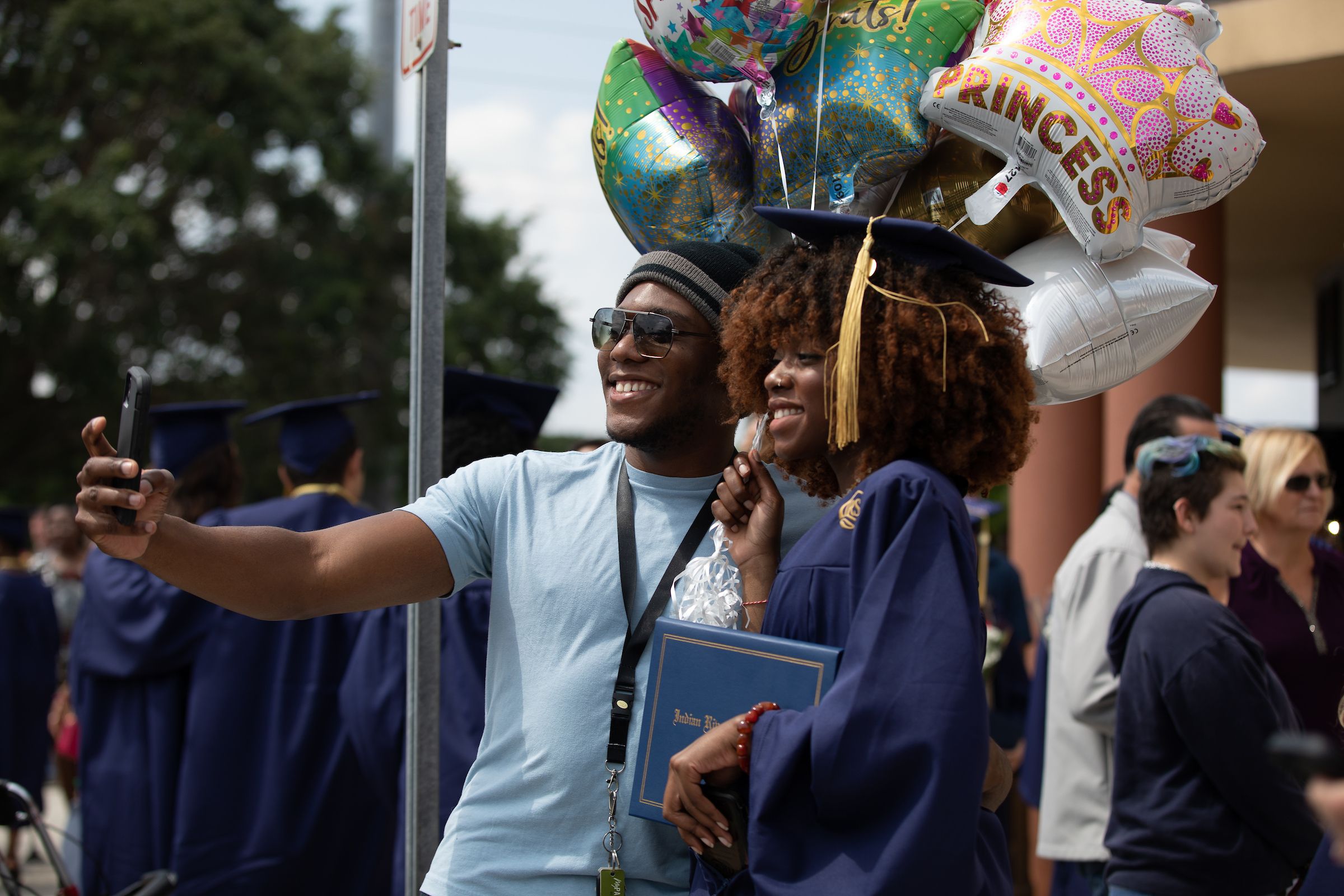 Person taking a selfie with college graduate in cap and gown.