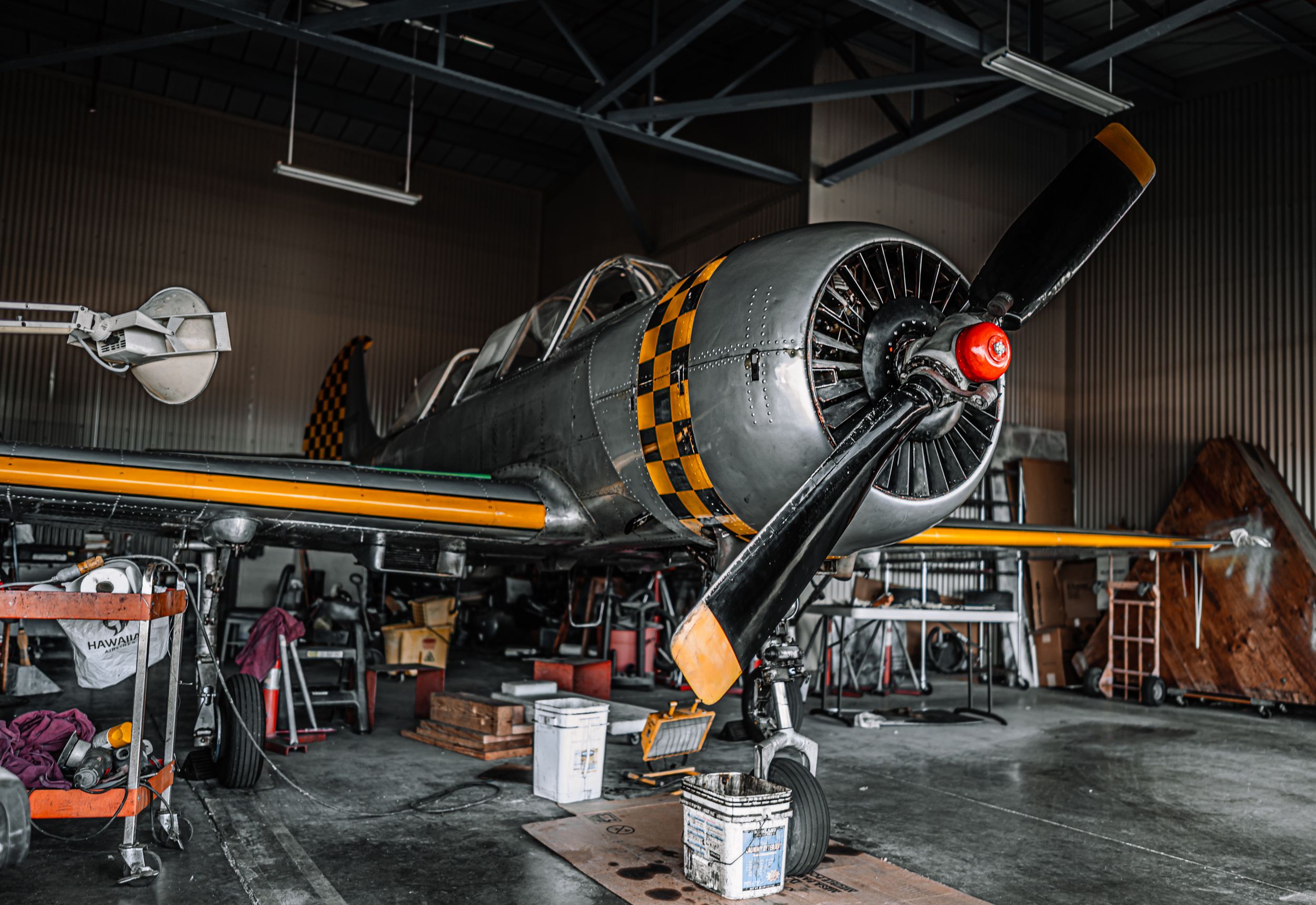 Retro propeller aircraft under mechanicla service in plane hanger.