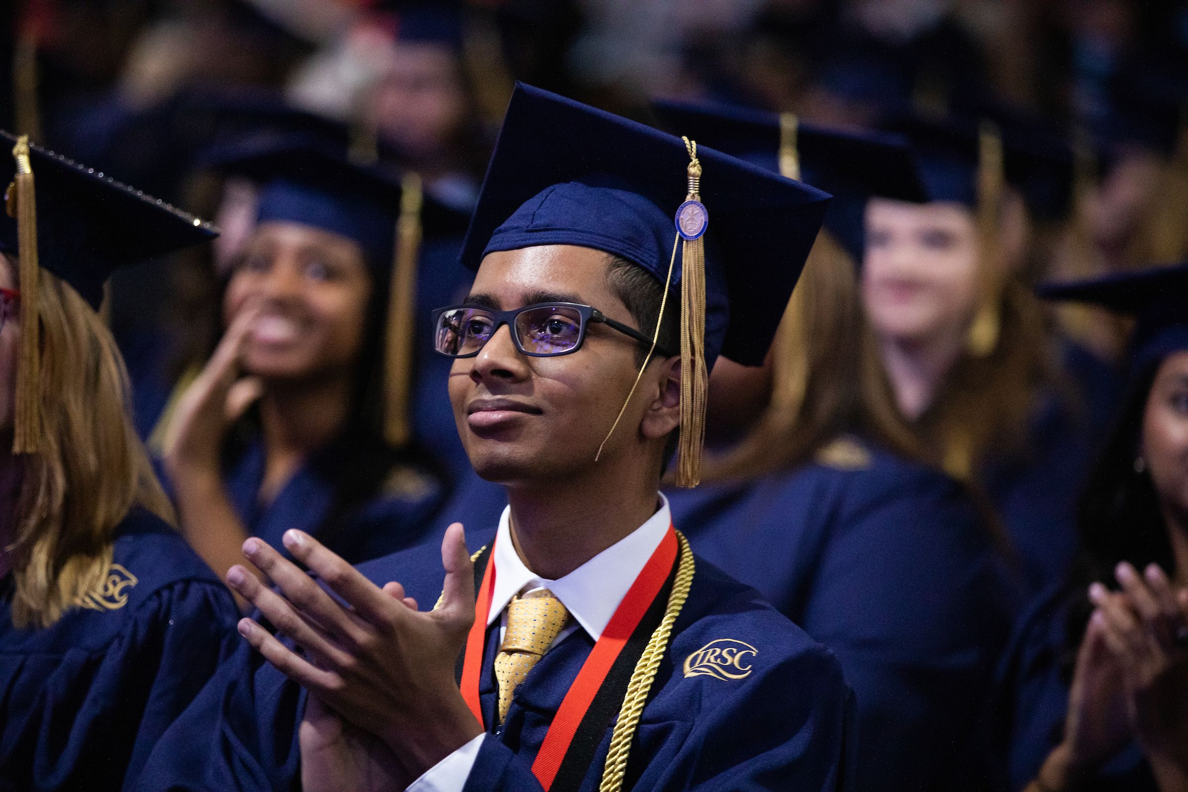 Person clapping in a cap and gown during their graduation.