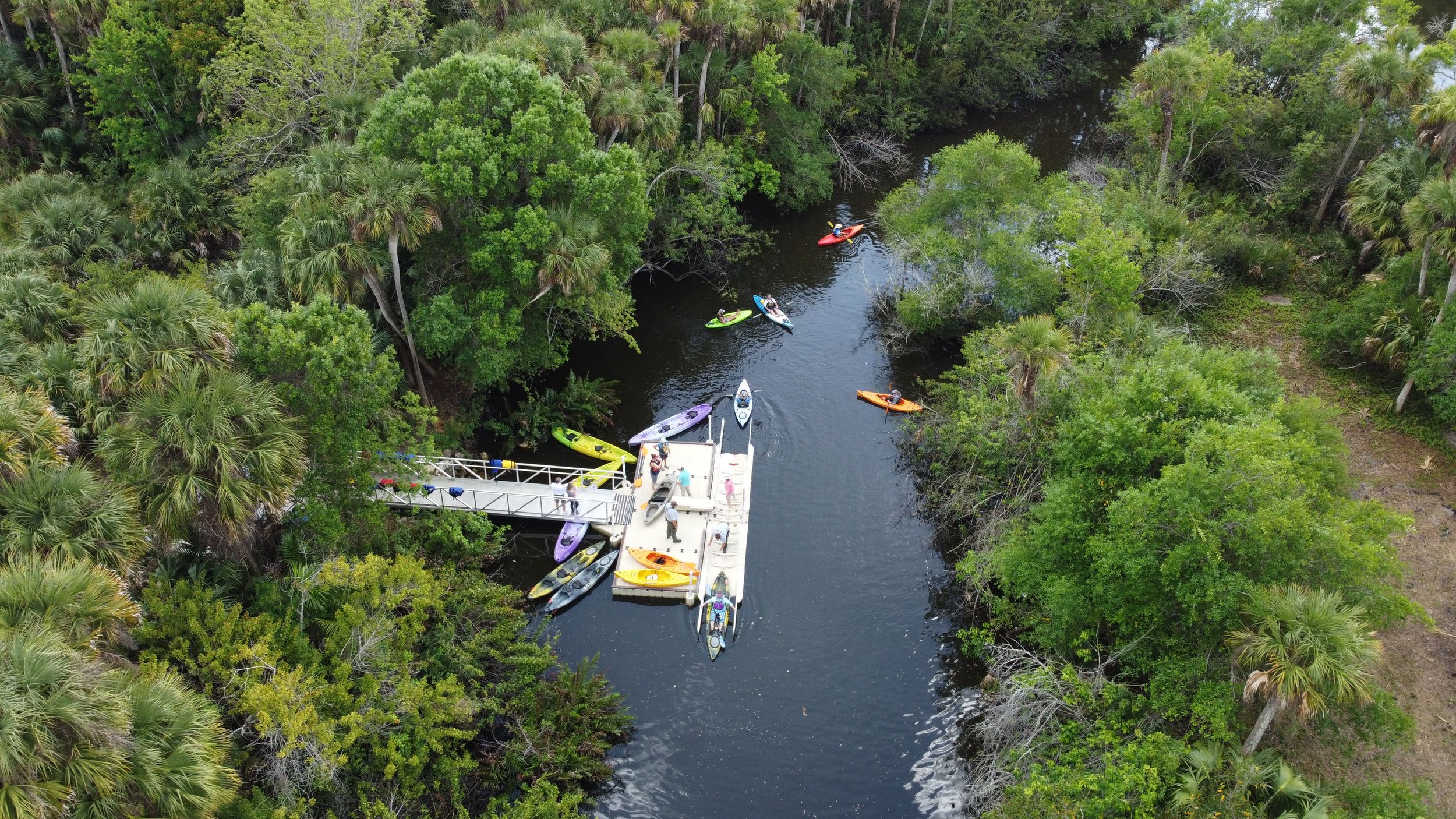 Aerial of people getting in and out of colorful kayaks on Indian River Lagoon.