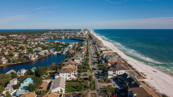 Aerial of houses and a long road by the beach.